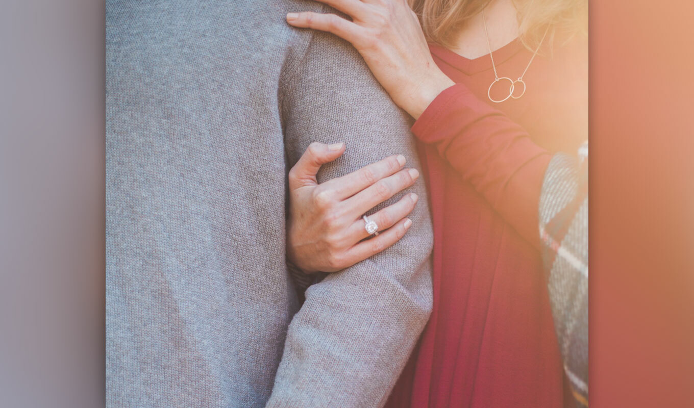 close-up image of a woman holding her partner's arm, overcoming feeling alone in their marriage