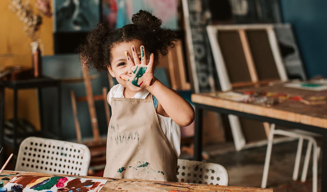 photo of a young only child girl holding up her hands to show finger painting