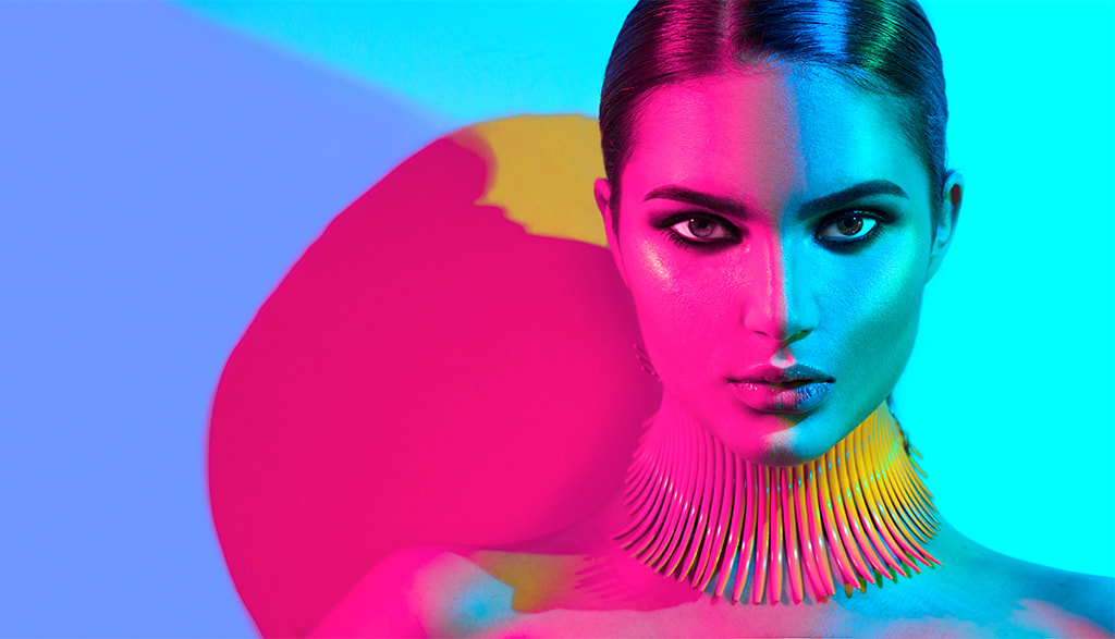 attractive model wearing metallic makeup and striking a serious pose against colorful background, pretty privilege concept