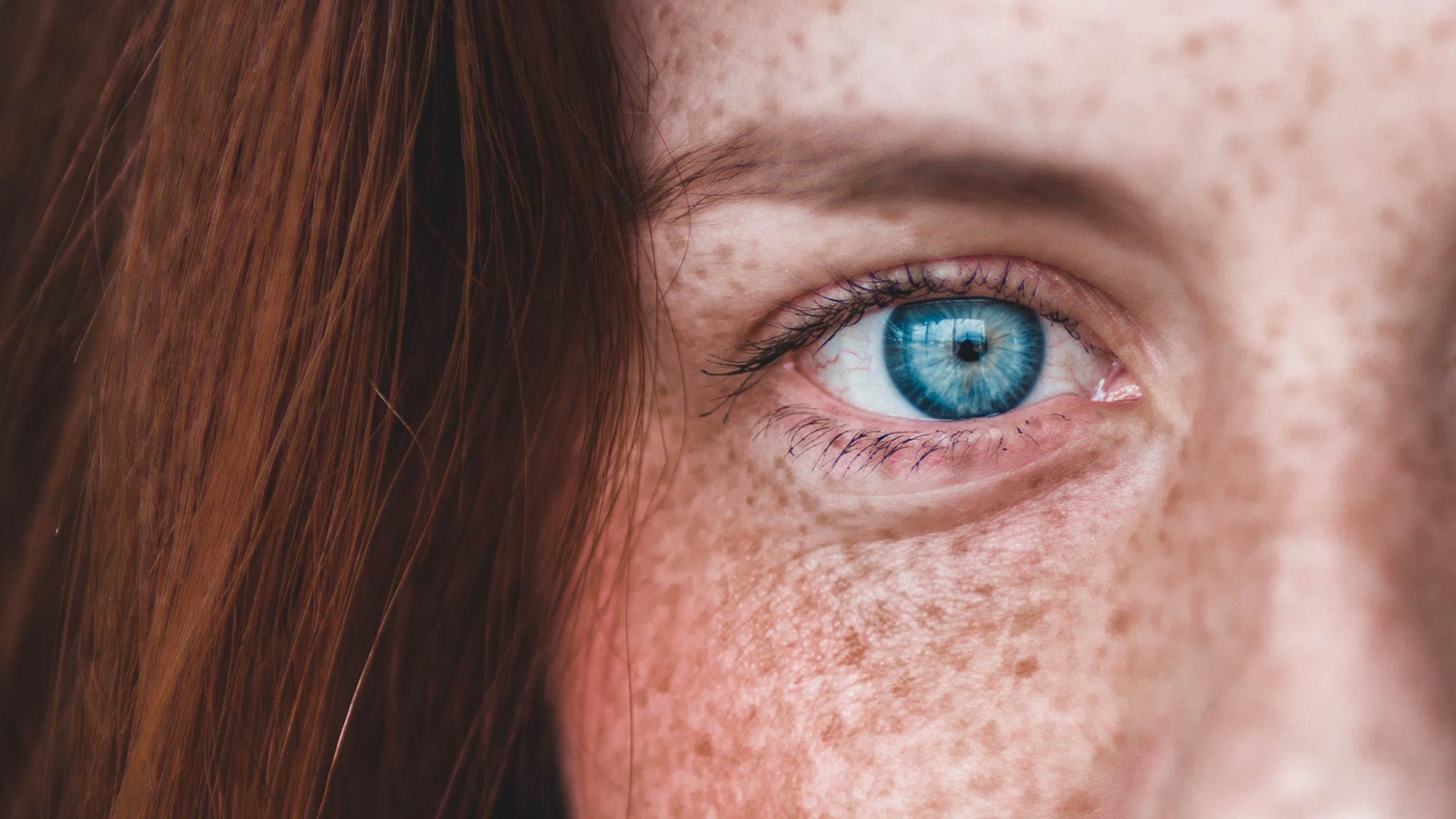 Closeup Photograph Of Freckled Woman Staring Intently Into The Camera Lens