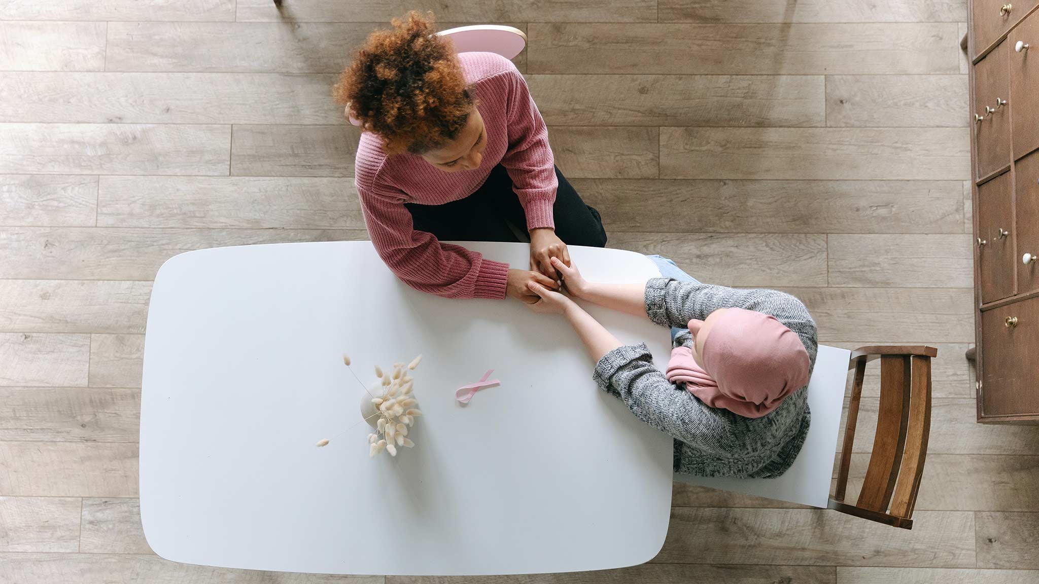 Aerial Photograph Of Caregiver Gently Holding The Hands Of A Cancer Patient Sitting Across The Table