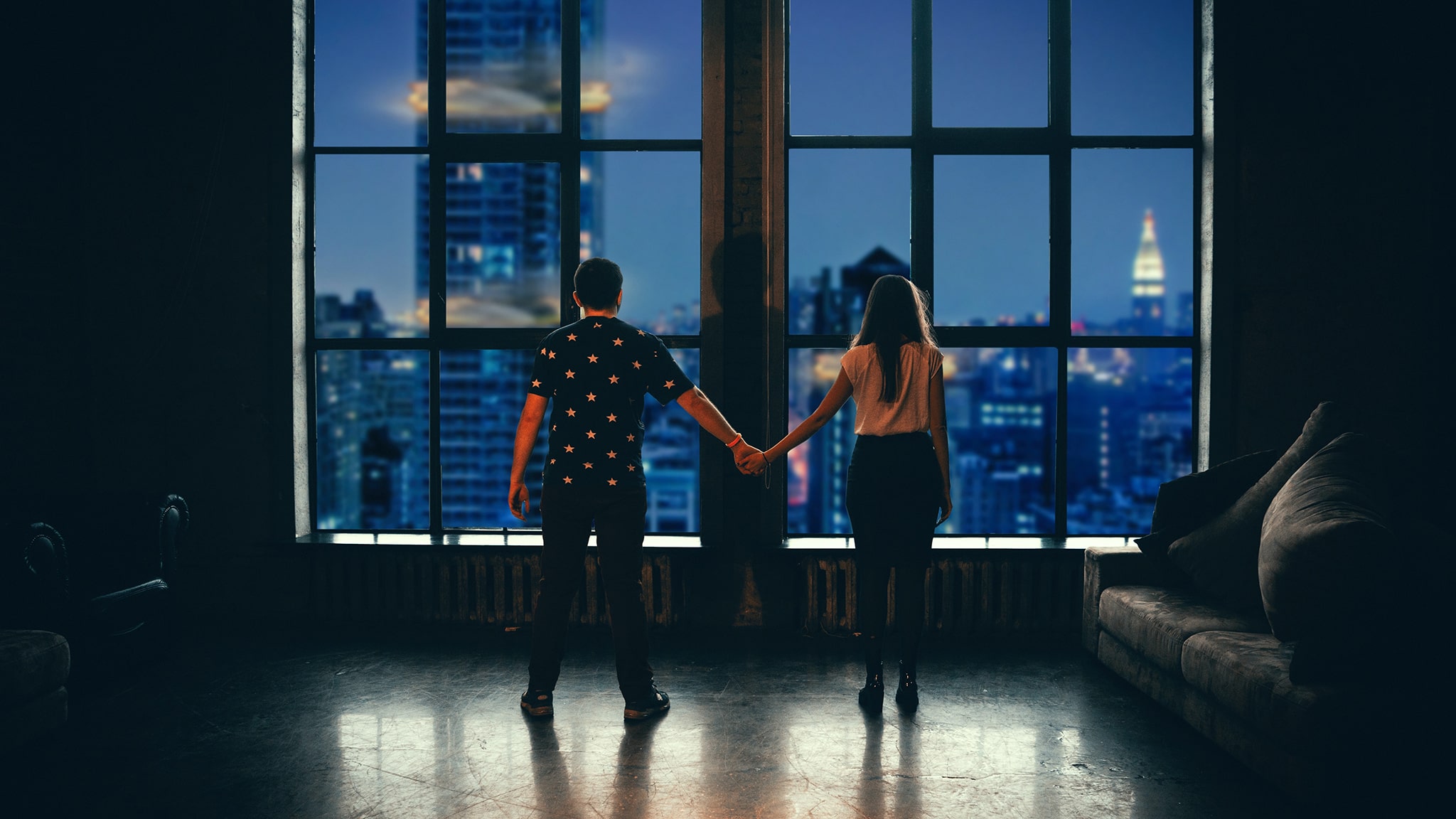 What Causes Romantic Loneliness And How To Overcome It Photograph Of Man And Woman Standing Apart While Holding Hands And Looking Over A Cityscape From Their Apartment