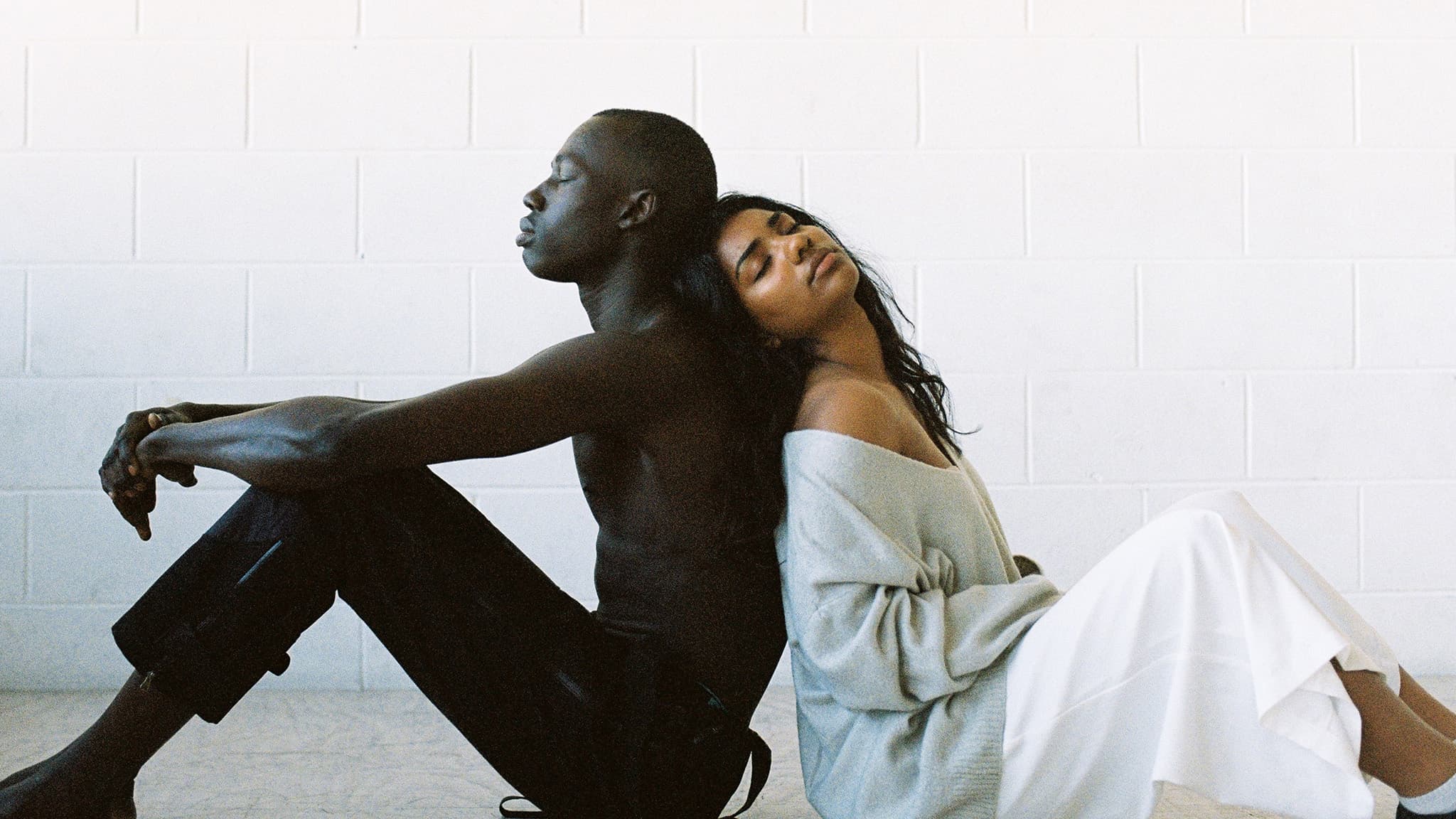 photo of couple sitting back to back to deal with feeling lonely in a relationship together