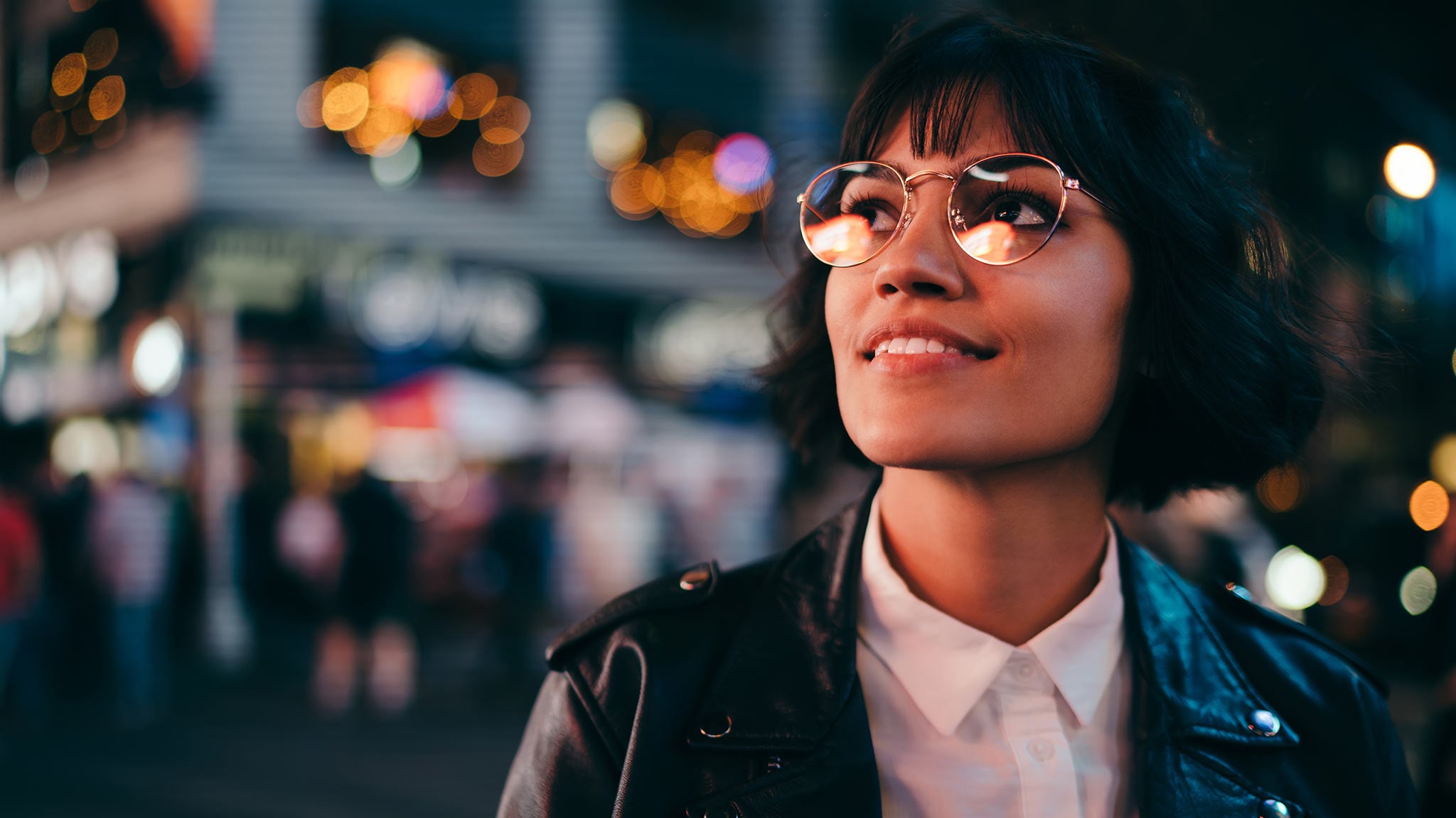 Headshot Of Young Woman Looking Up At Surrounding City Lights At Night