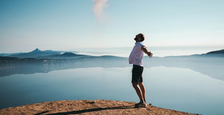 photo of man standing next to water, arms stretched out to symbolize hope for alleviating bpd loneliness