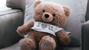 Closeup Photograph Of Teddy Bear Wearing "I Heart U" T-Shirt While Sitting On A Chair