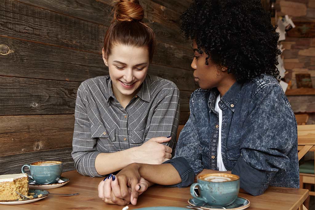 photo of lesbian couple bonding in a coffee shop, feeling less alone with each other