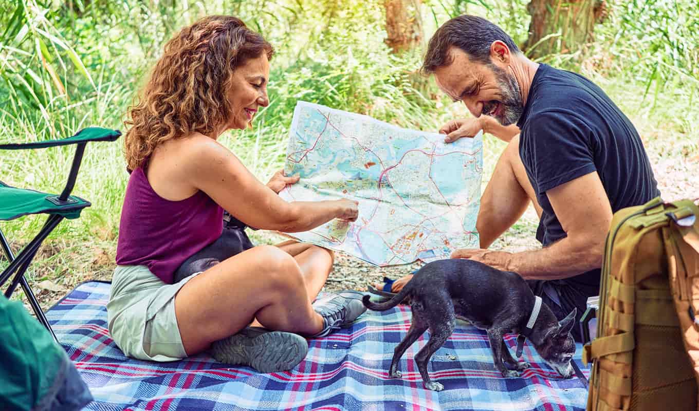 photograph of a couple looking at a map while camping, spending time together to ease the loneliness of midlife and reclaim their happiness together