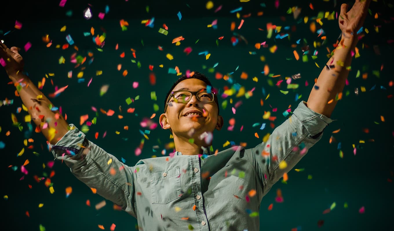 photo of happy man spreading hands in a sea of confetti, spending a happy birthday alone