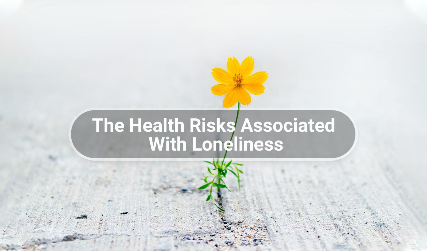 yellow flower growing through crack in the pavement with text overlay that reads the health risks associated with loneliness