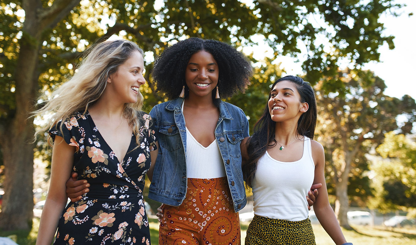 Photograph Of Multi-Racial Women Walking Together Closely In A Park-Like Setting