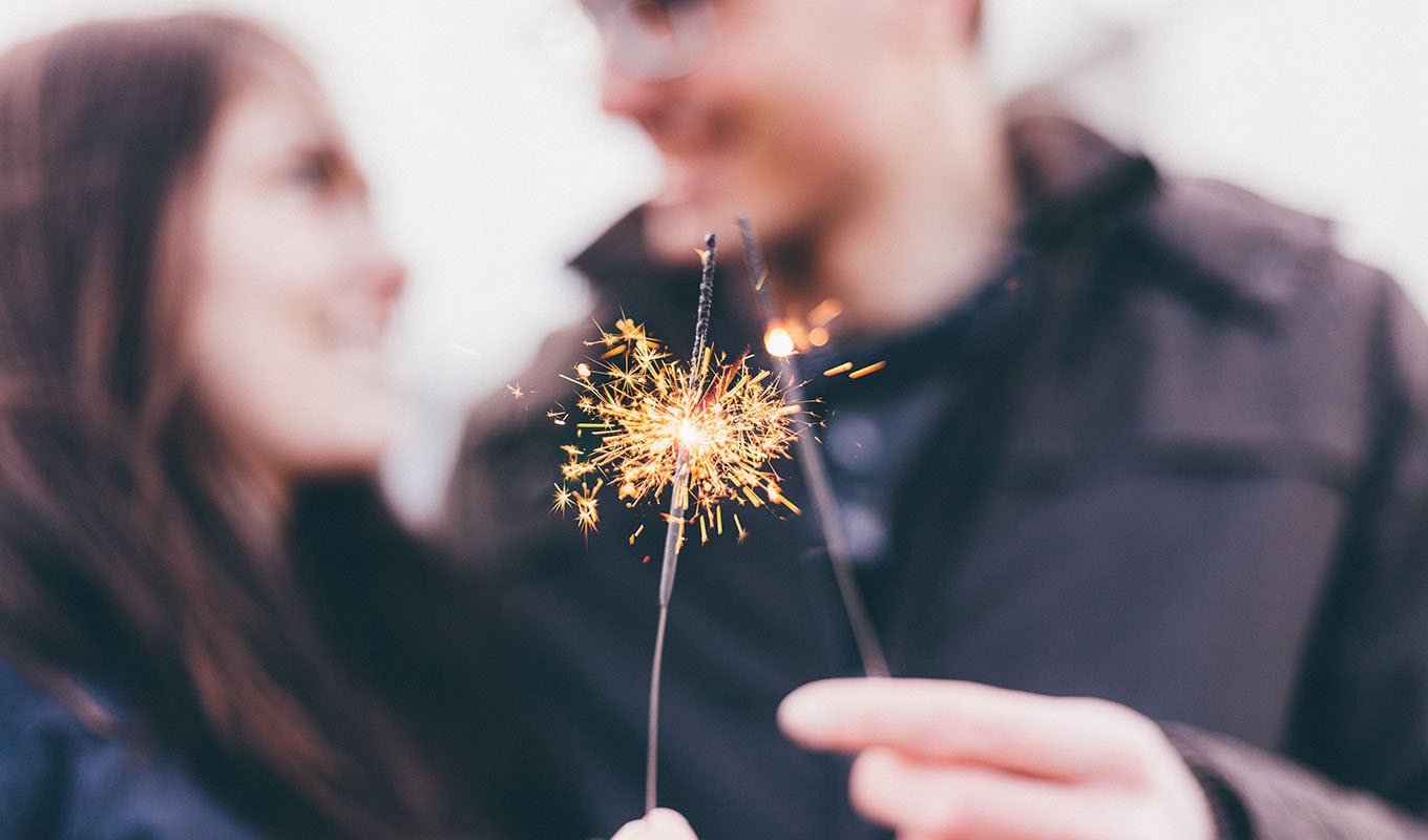 photo of two lit sparklers in front of a man and woman overcoming their loneliness in their romantic relationship