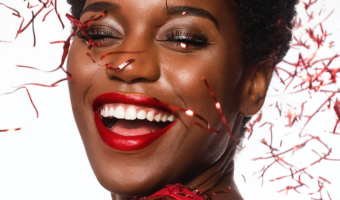 Close Up Photograph Of Smiling Woman Covered In Red Glittery Confetti, Celebration Concept