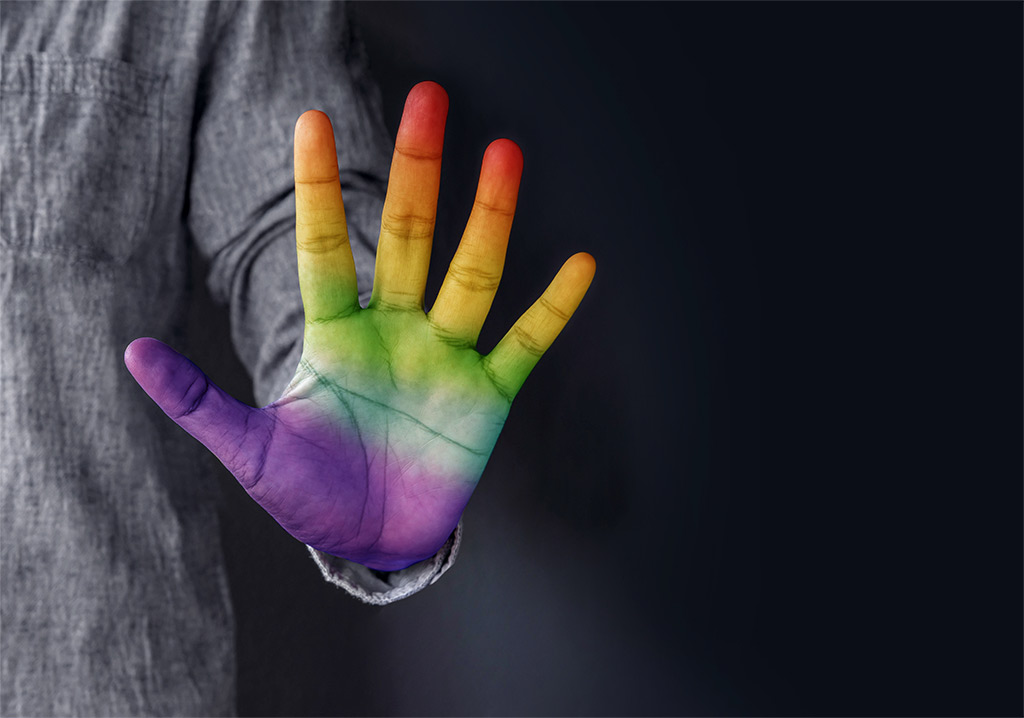 Closeup Photo Of A Man's Open Hand Tinted in Rainbow Colors Across The Palm And Fingers