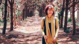 Photograph Of Young Asian Woman Content While Walking Alone Down Tree-Lined Path