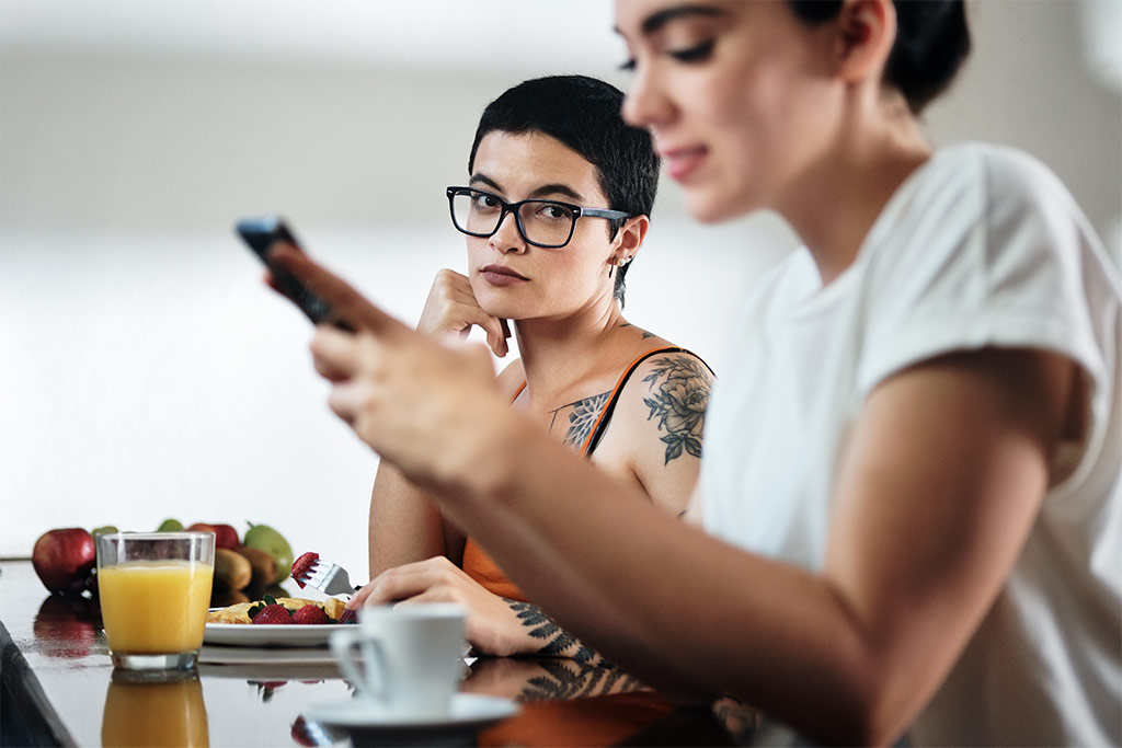 Photograph Of Young Woman Wistfully Looking At Another Woman Who Is Busy Staring At Her Phone